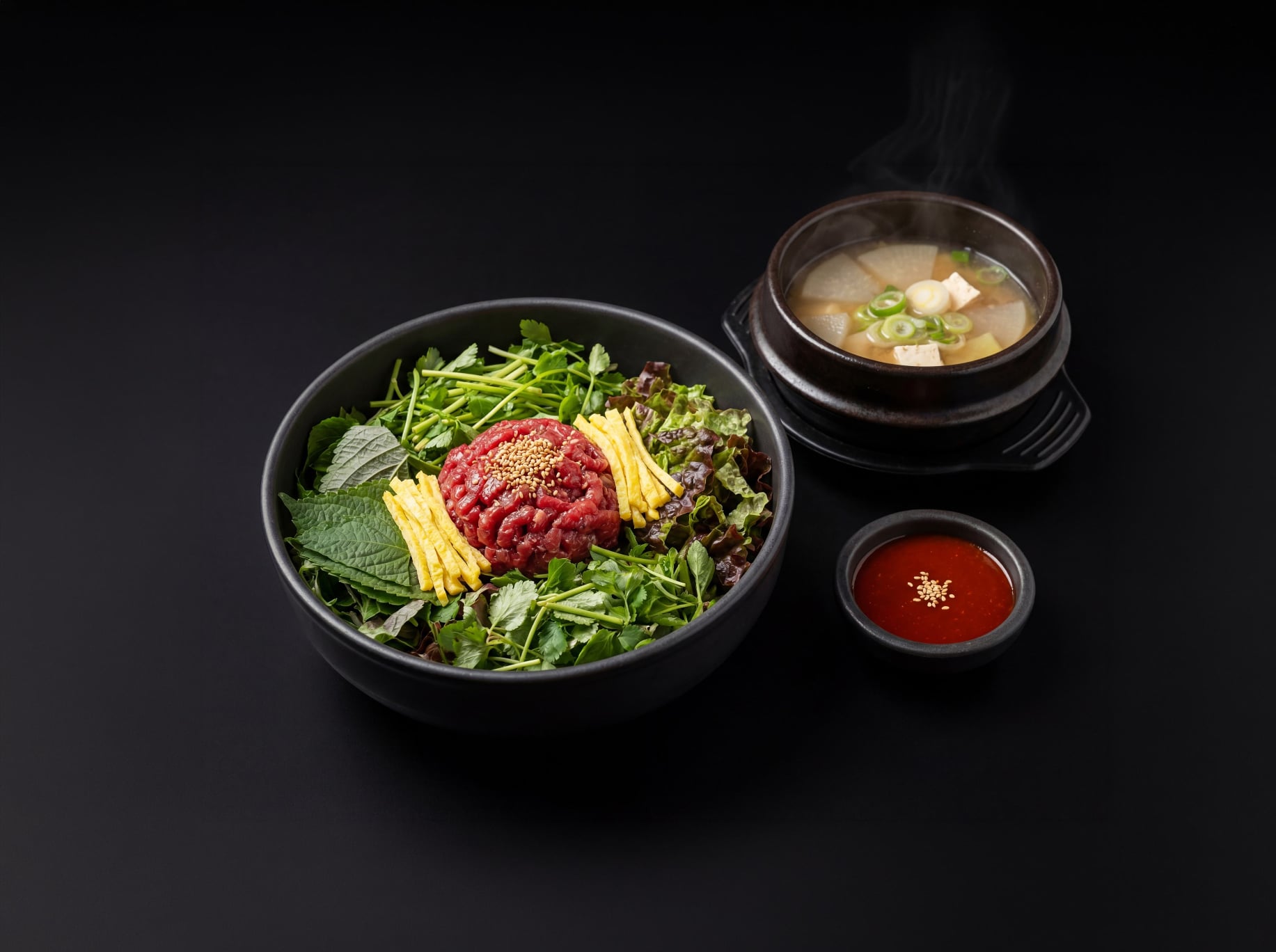 다크 배경의 육회비빔밥과 김이 오르는 국