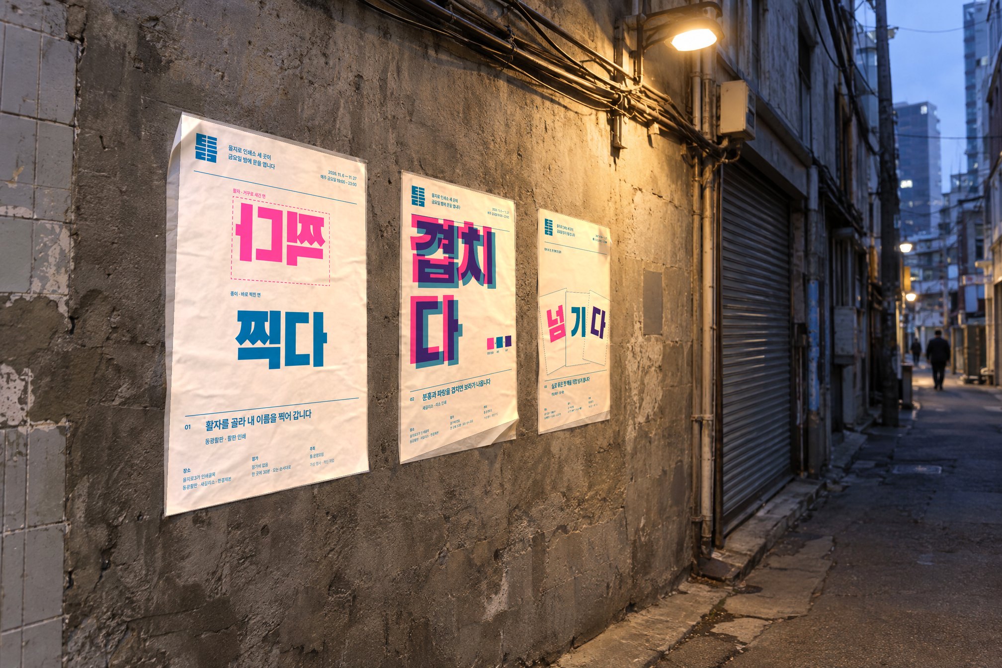 가로등 아래 콘크리트 골목 벽에 나란히 붙은 포스터 세 장